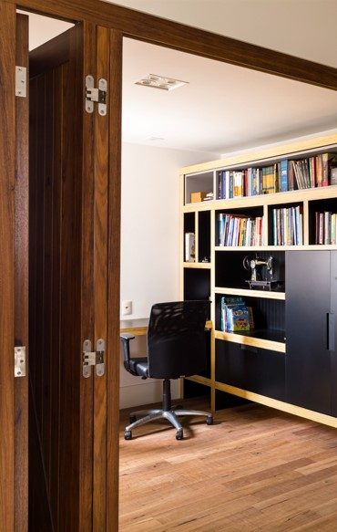 Home office com estante sob medida em madeira e porta pivotante