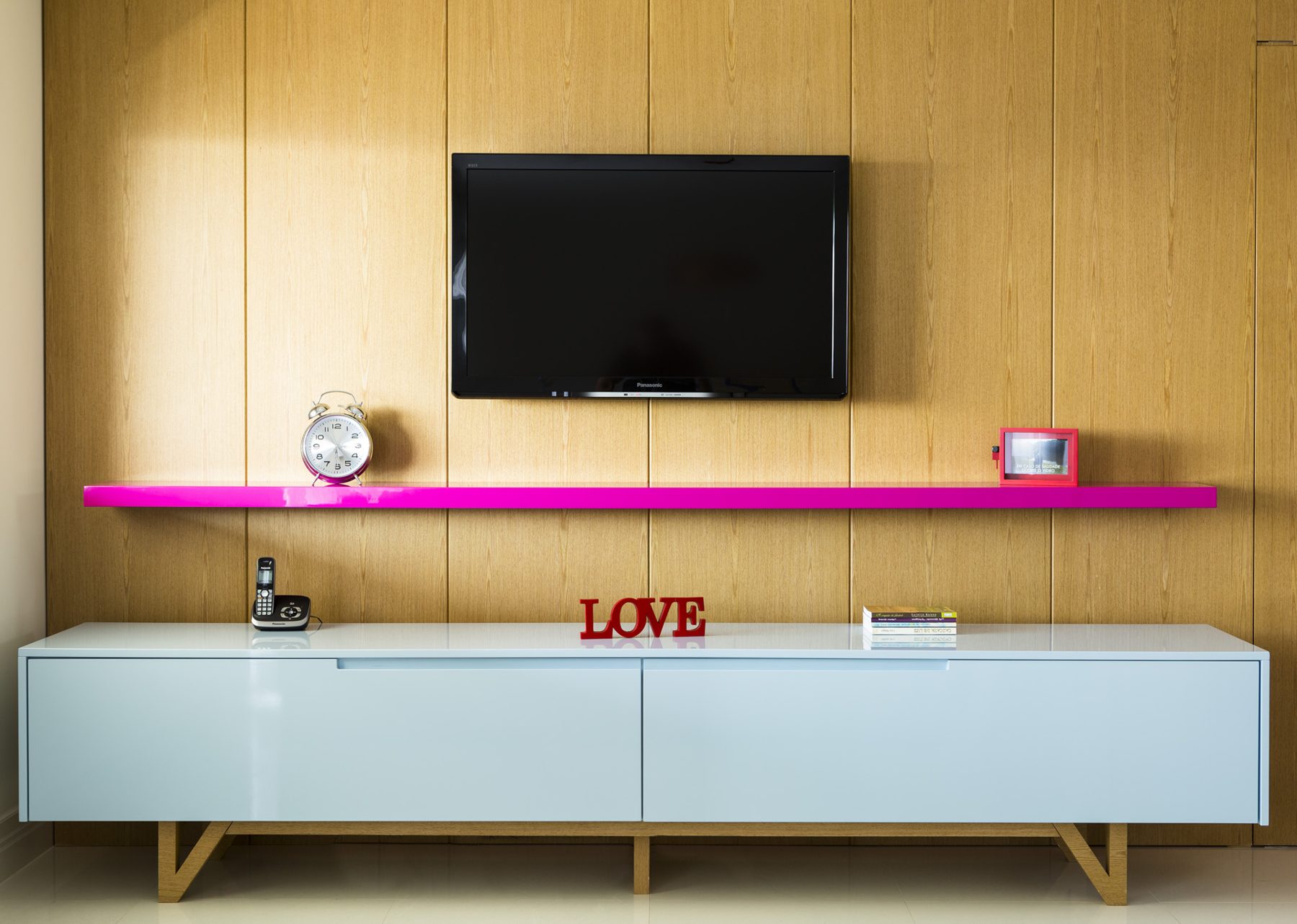 Painel de madeira com rack branco e prateleira pink