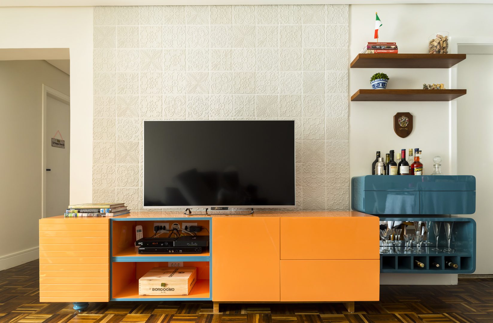 Sala de TV com rack laranja laqueado e bar azul